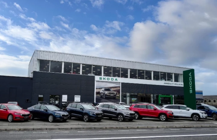 outside of car showroom, showing lineup of new cars for sale